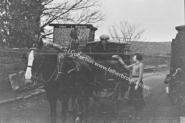 MAN WITH CARRIAGE PAYING TOLL TO YOUNG WOMAN